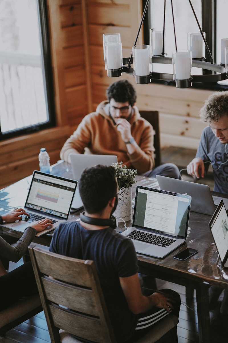 A diverse team collaborating on digital marketing strategies at a desk, using laptops and tablets.
